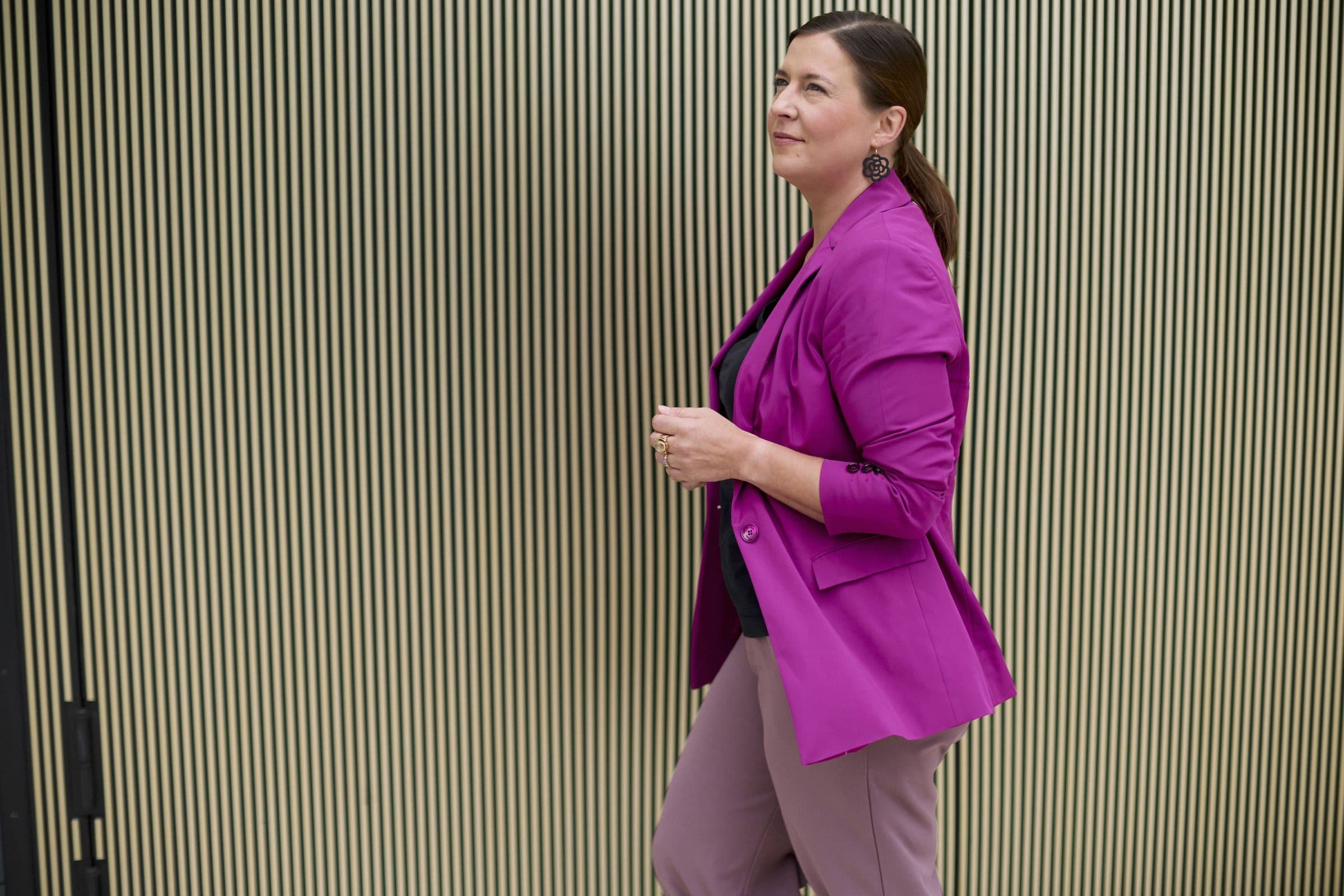 Nele Traen geht zielstrebig an einer goldenen Lamellenfassade entlang