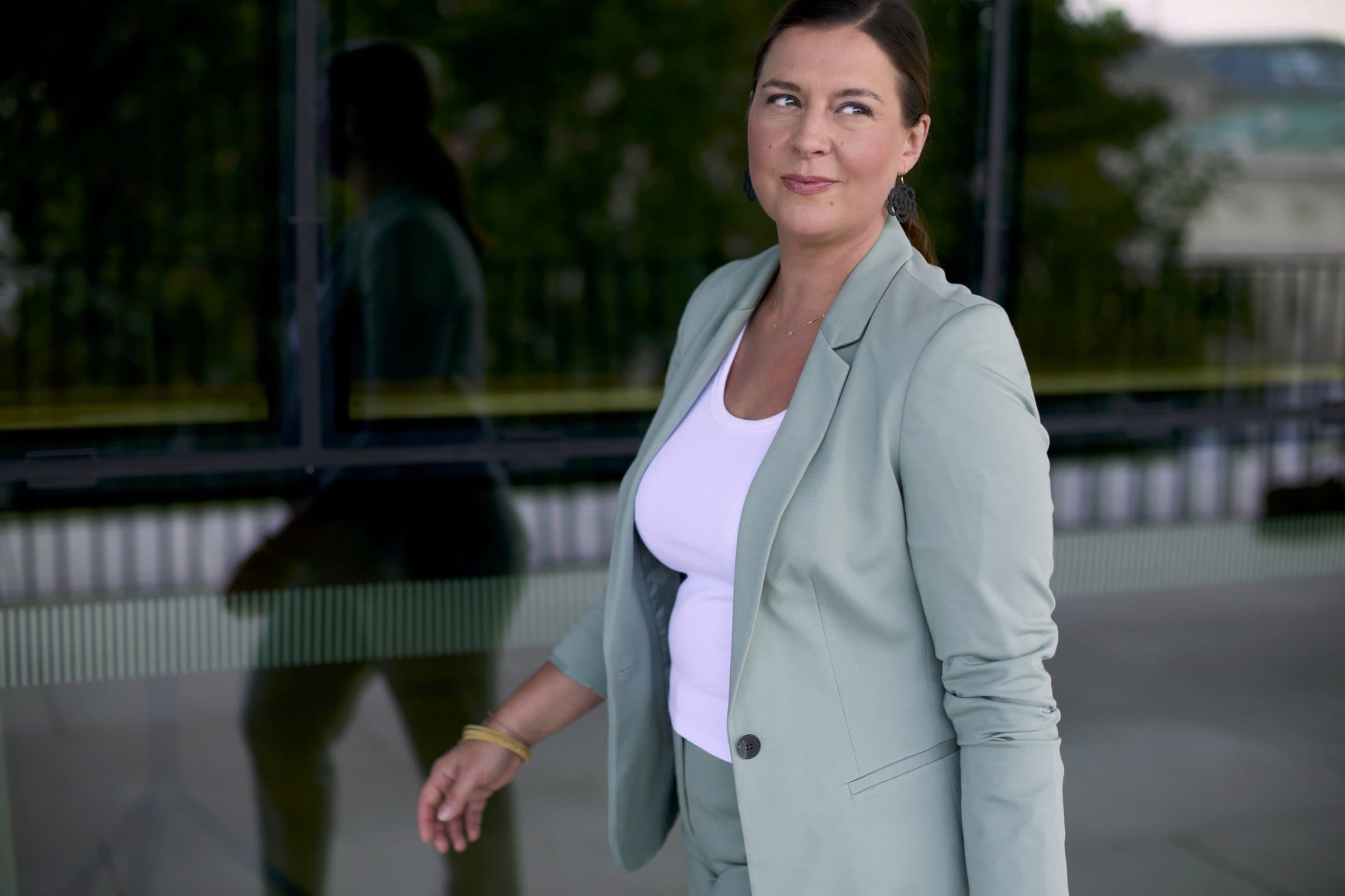 Nele Traen telefoniert vor einer modernen Glasfassade